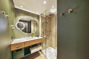 埃施伯恩H+ Hotel Frankfurt Eschborn的带淋浴、盥洗盆和镜子的浴室