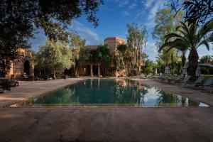 马拉喀什Villa Al Assala Palmeraie的公园内的游泳池,有椅子和树木
