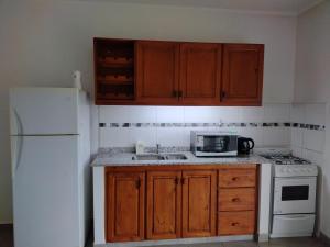 瓜莱瓜伊La casita de Isa的厨房配有木制橱柜和白色冰箱。