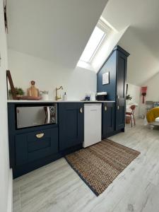 韦克斯福德The Loft Curracloe, on Wexfords Coastal Scenic Route的厨房配有蓝色橱柜、水槽和洗碗机。