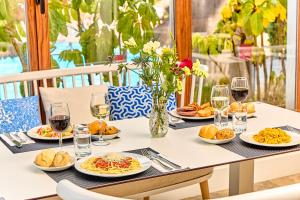 埃斯卡纳Leonardo Suites Hotel Ibiza Santa Eulalia的餐桌,带食物盘和酒杯