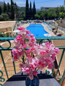 帕莱欧卡斯提撒Maria Studios的游泳池畔的一张桌子上摆放着粉红色花卉的花瓶