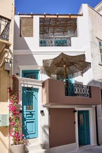 埃尔莫波利斯Syroc Maison的一座带蓝色门和雨伞的建筑