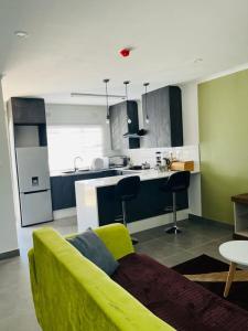 哈博罗内Comfy Zone Apartment的一间带黄色沙发的客厅和一间厨房
