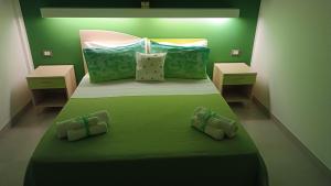 纳尔多Il giardino dei tramonti的绿色卧室配有一张大床,配有绿色床单和枕头