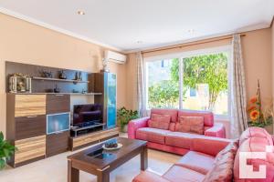 卡尔佩Villa Casanova - Grupo Turis的客厅配有粉红色的沙发和电视