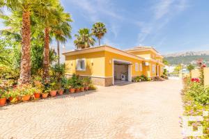 卡尔佩Villa Casanova - Grupo Turis的棕榈树和车道的黄色房子