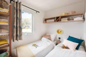 Lansargues乐夫都罗伊露营地假日公园的一间卧室设有两张床和窗户。