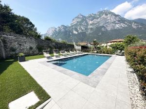 加尔达湖滨Residence Zangirolami - Luxury Garden and Balcony Apartments的一个带椅子的游泳池,后方是一座山。