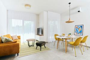 乌马格Apartments San Maris 2的客厅配有桌子和黄色椅子