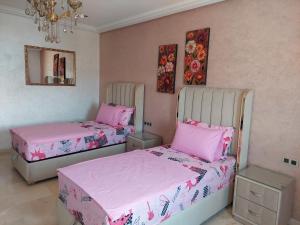 纳祖尔Residence La corniche Étage 2的配有粉红色床单的客房内的两张床