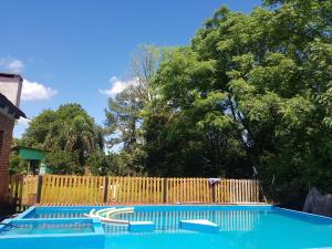 Leandro N. AlemBELLA CASA EN VILLA LIBERTAD的蓝色的游泳池,带有木栅栏和树木