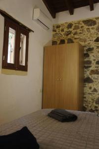 AmigdhalokeFálionRosales stone house的一间卧室配有一张床和一个木制橱柜