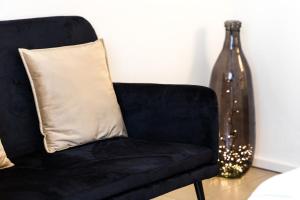 托尔博莱Carly's Rooms的配有枕头和玻璃花瓶的黑椅子