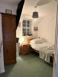 波尔泽斯Shilla Mill - Just off the Beach的一间卧室配有一张床和一个木制橱柜