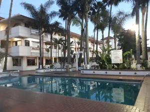 恩塞纳达港Hotel Paraiso Las Palmas的棕榈树建筑前的游泳池