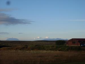 VíðirhóllGrímstunga Guesthouse的远处有一座红色房子和山地