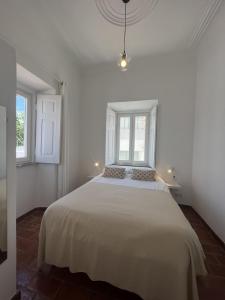 Montes de AlvorGuesthouse Casa Felicia的白色卧室设有一张大床和两个窗户