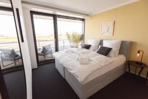 不来梅港Bheaven I Marina Premium Apartment的一间带一张白色大床的卧室和一个阳台