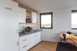 不来梅港Bheaven I Marina Premium Apartment的厨房配有白色橱柜和桌子