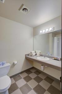 洋滨市Pacific Sunrise Inn & Suites的一间带卫生间、水槽和镜子的浴室