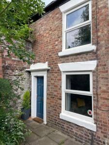 麦克尔斯菲尔德Tucked away house in Macclesfield的砖屋,设有两扇窗户和一扇蓝色的门