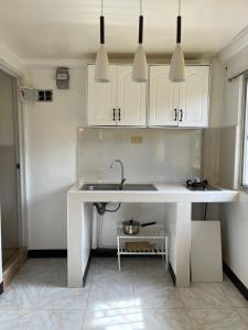 马斯巴特Maria Kulafu Studio Apartment Kinamaligan- Beside Eglin Gas FREE Wifi的白色的厨房配有水槽和白色橱柜