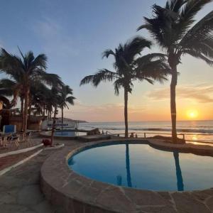 曼克拉Hotel Casa Mediterranea Mancora的棕榈树海滩旁的游泳池