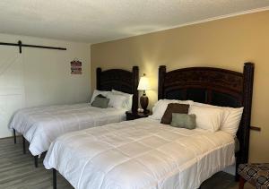 布兰森Ballparks Inn的一间卧室配有两张带白色床单的床