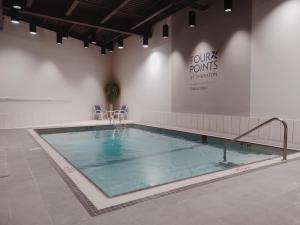 埃德门兹顿Four Points by Sheraton Edmundston Hotel & Conference Center的一个带椅子的大型游泳池