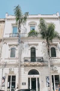 布林迪西Appartamenti Luxury Greco的两棵棕榈树的白色建筑