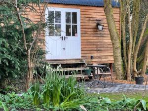 CinderfordTranquil Spot Shepherds Hut的小木屋设有白色门和长凳