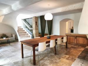 卢马罕Mas provençal, parc de 6000m2, Lourmarin à pied的一间带木桌和白色椅子的用餐室