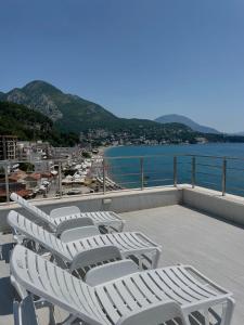 苏托莫雷Hotel Kaligrosh的阳台上摆放着一排白色的躺椅,俯瞰着大海
