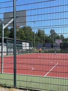赫尔辛基Puotilan idylli meren lähellä的两人在网球场打网球