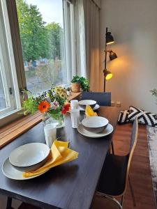 赫尔辛基Puotilan idylli meren lähellä的一张木桌,上面放有盘子和鲜花