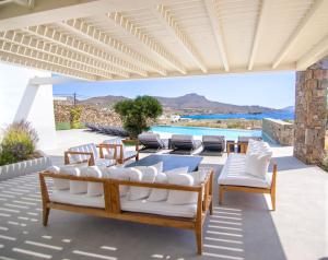 卡拉法蒂斯Blue Eye Grand Villa Mykonos的一个带桌椅的庭院和一个游泳池