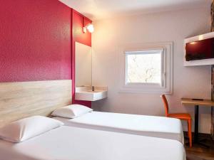 巴黎巴黎沙蒂永门F1酒店的客房设有两张床、一个水槽和窗户。