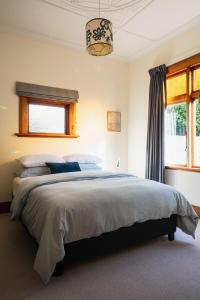 但尼丁Cottage on Aotea的一间卧室设有一张大床和一个窗户。