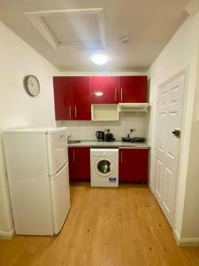 伦敦Penthouse studio with 2 double beds & smart TV. Great London Location的厨房配有红色橱柜和白色冰箱