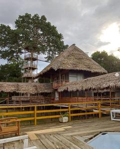 伊基托斯Ceiba Amazon Lodge的一座带稻草屋顶的建筑和一座带椅子的建筑