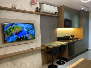 瓜鲁柳斯Studio I Patteo Bosque Maia的墙上的厨房,配有电视机和柜台