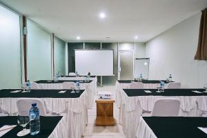 库塔Horison Kuta Bali的一间会议室,配有桌椅和屏幕