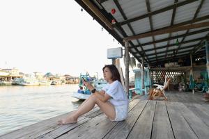 春蓬Rub Lom Chom Klong Homestay的坐在水边码头上的年轻女孩