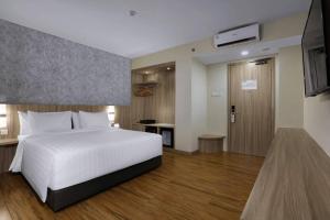 巴淡岛中心ASTON Nagoya City Hotel的卧室配有白色的床和电视。