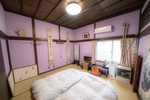小樽小樽民泊太田1号館的紫色墙壁客房里一间卧室,配有一张床