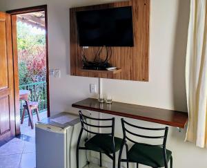 戈亚斯州上帕莱索Pousada Casa Rosa的一间设有酒吧的房间,配有两把椅子和一台电视