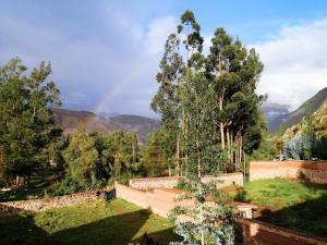 乌鲁班巴Cozy mountain house的山中带有墙和树木的彩虹