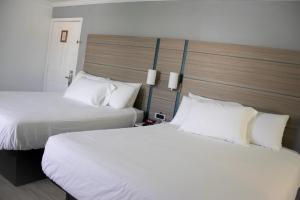 海沃德迪斯科瓦利旅馆的配有白色枕头的酒店客房内的两张床