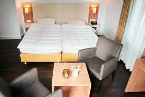 埃森胡格尔公园之家酒店的酒店客房配有一张床、两把椅子和一张桌子